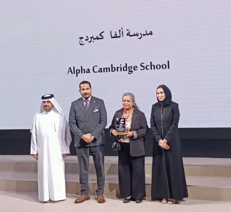 Alpha Cambridge School representatives on stage holding the Ministry of Education Clear Flag trophy